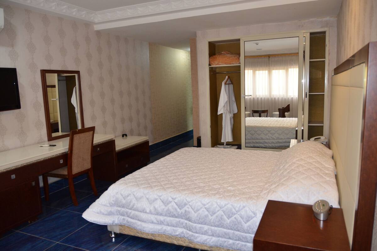 Ein Hotelzimmer mit Bett, Schreibtisch, Stuhl, Kleiderschrank und Spiegel.