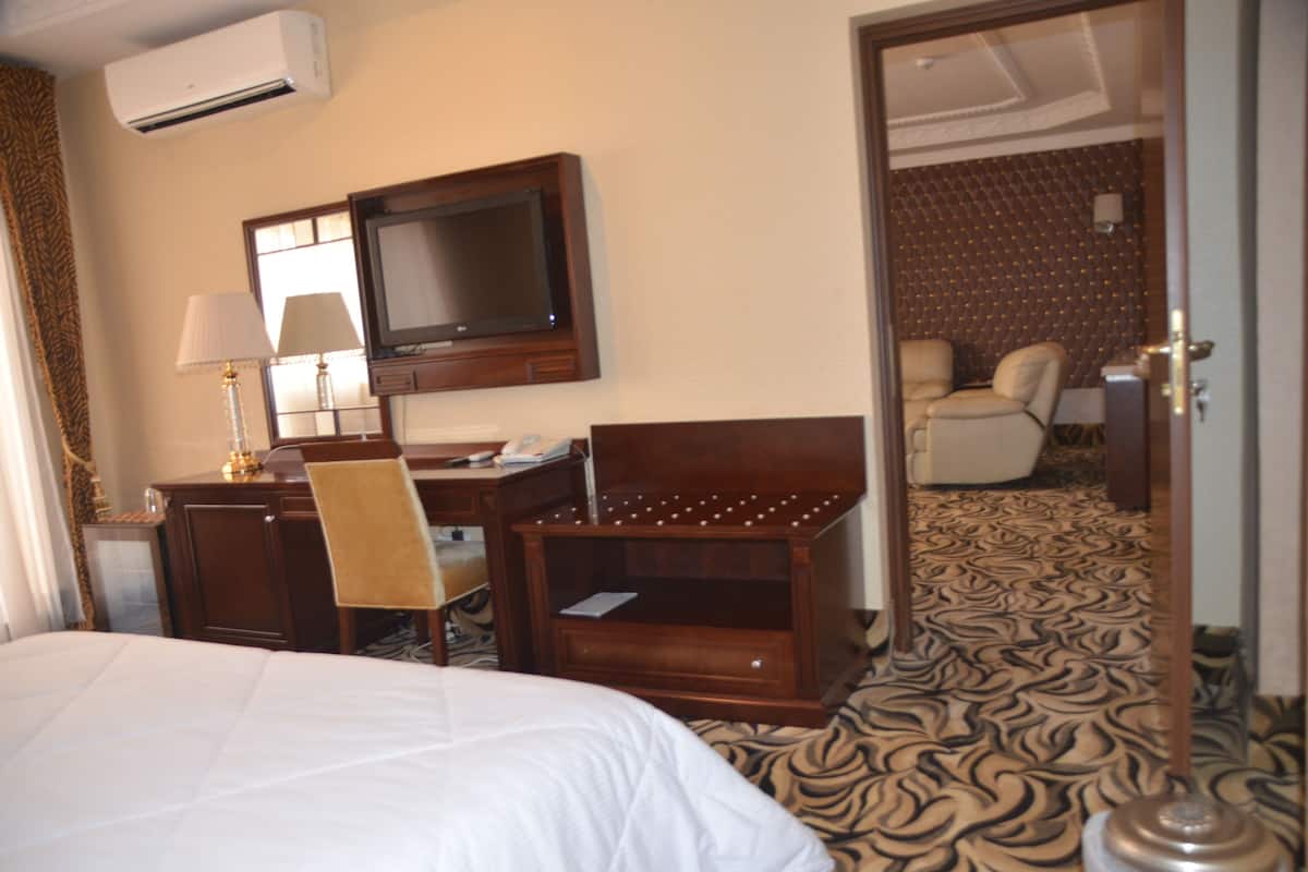 Ein Hotelzimmer mit Bett, Schreibtisch, Stuhl, Fernseher und einem durch eine offene Tür einsehbaren Badezimmer.