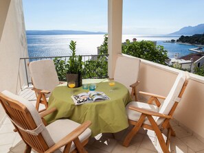 A balcony with a table set for two, featuring wooden chairs and a green tablecloth. - Apartment Ivanka (Brela)