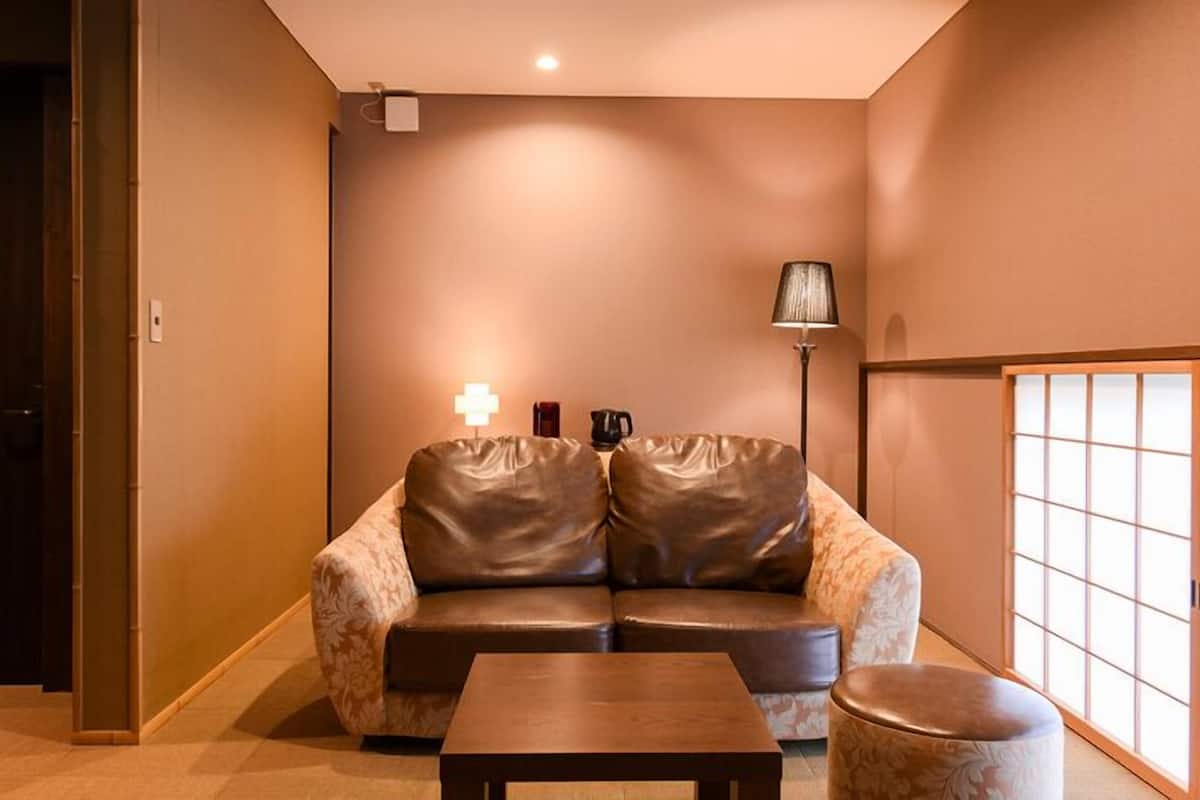 Una habitación con sofá, una mesita, una lámpara y una puerta corredera.