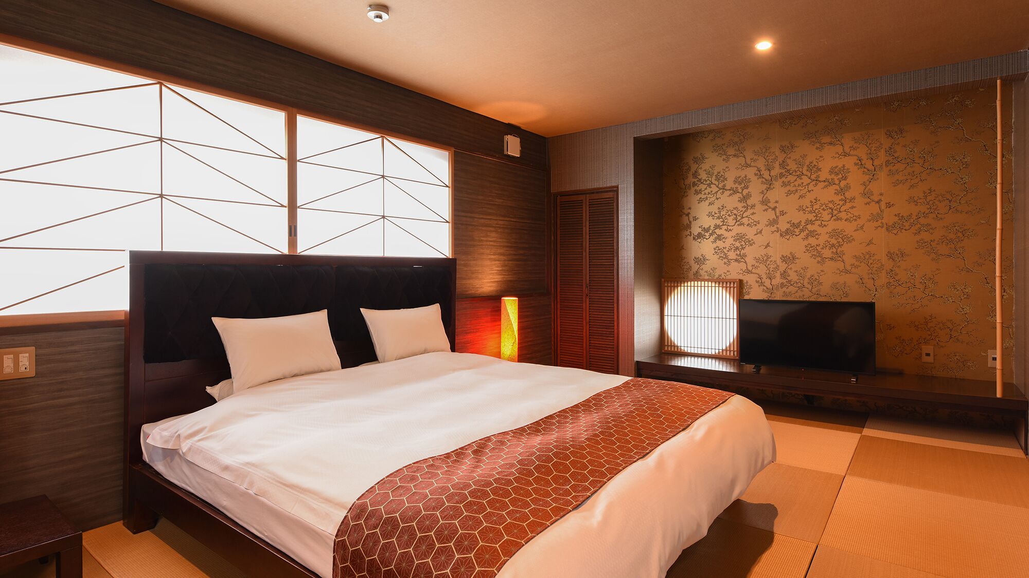 Een hotelkamer met een groot bed, een televisie en uitzicht door een raam.