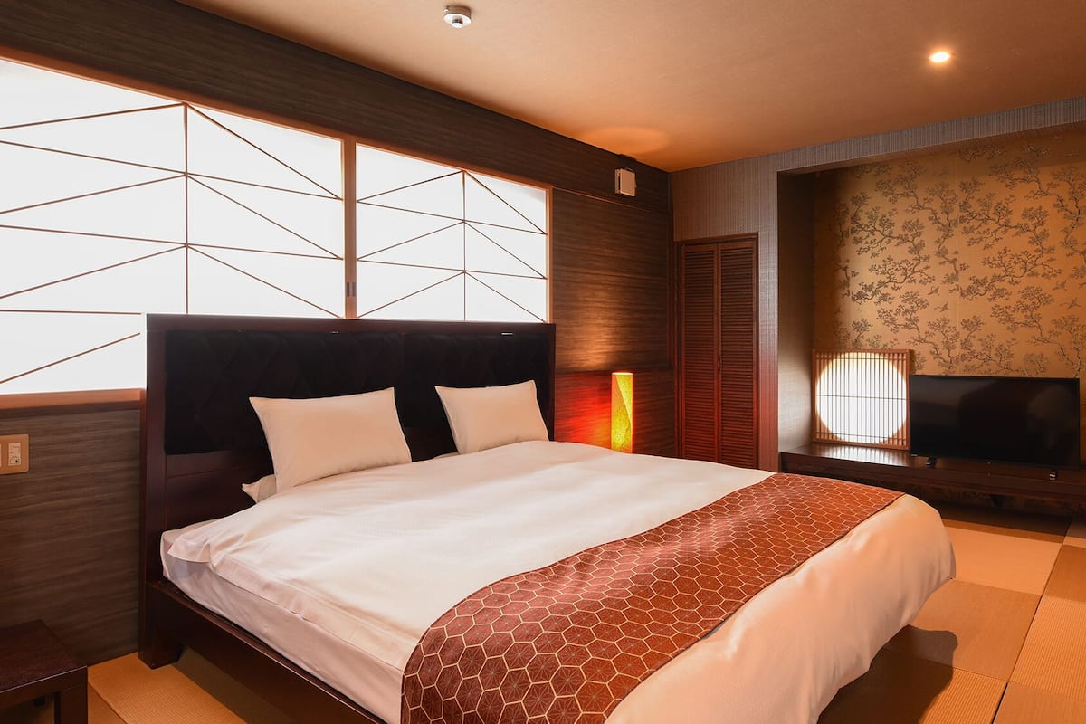 Habitación de hotel con una cama grande, televisión y vistas al exterior por una ventana.