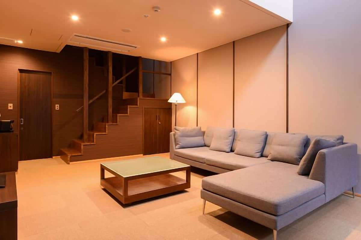 Una sala de estar moderna con un sofá modular, una mesa de centro y una escalera.