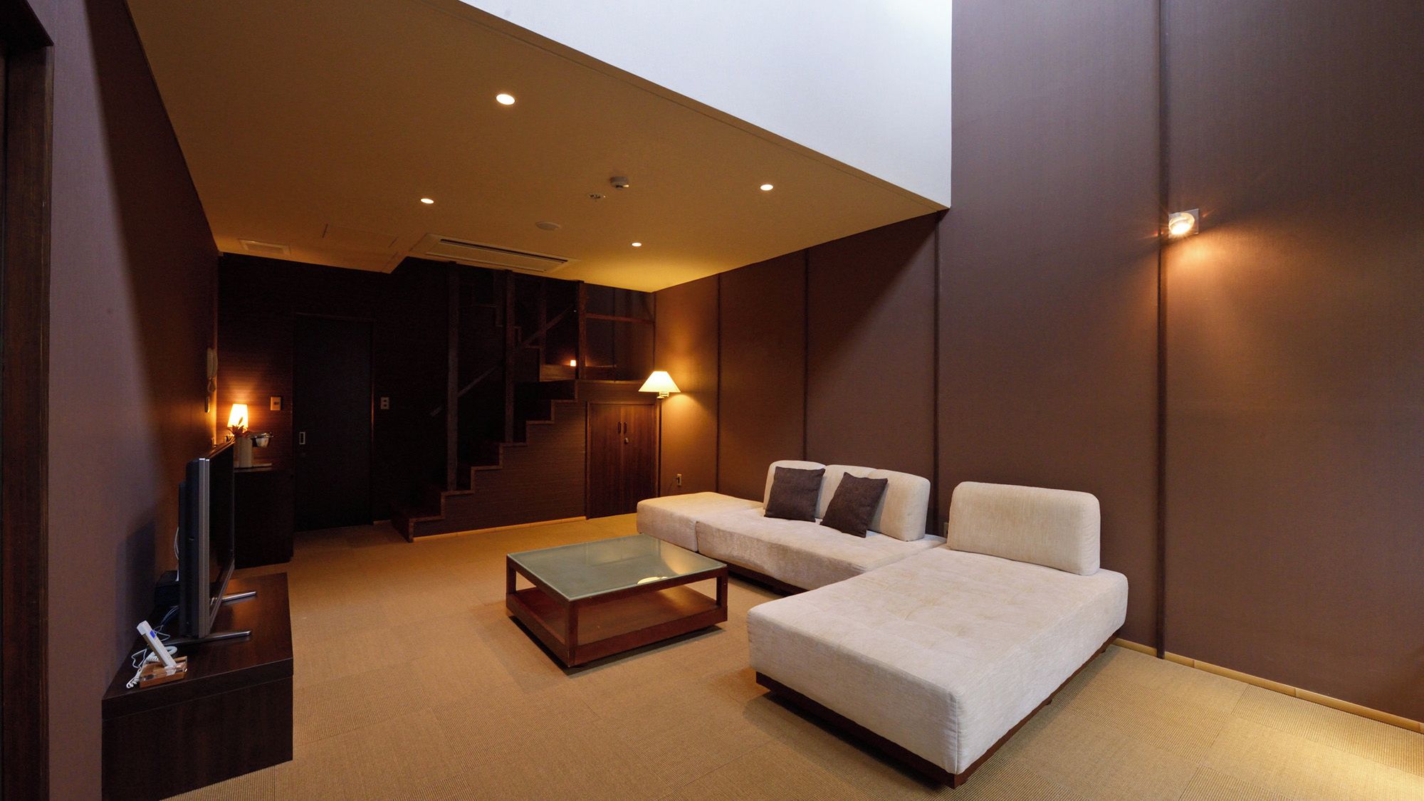 Una sala moderna con un sofá, una mesa de centro y un televisor sobre un mueble.