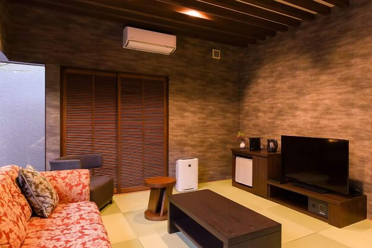 Una sala de estar con sofá, mesa de centro, televisor, refrigerador pequeño y un armario.