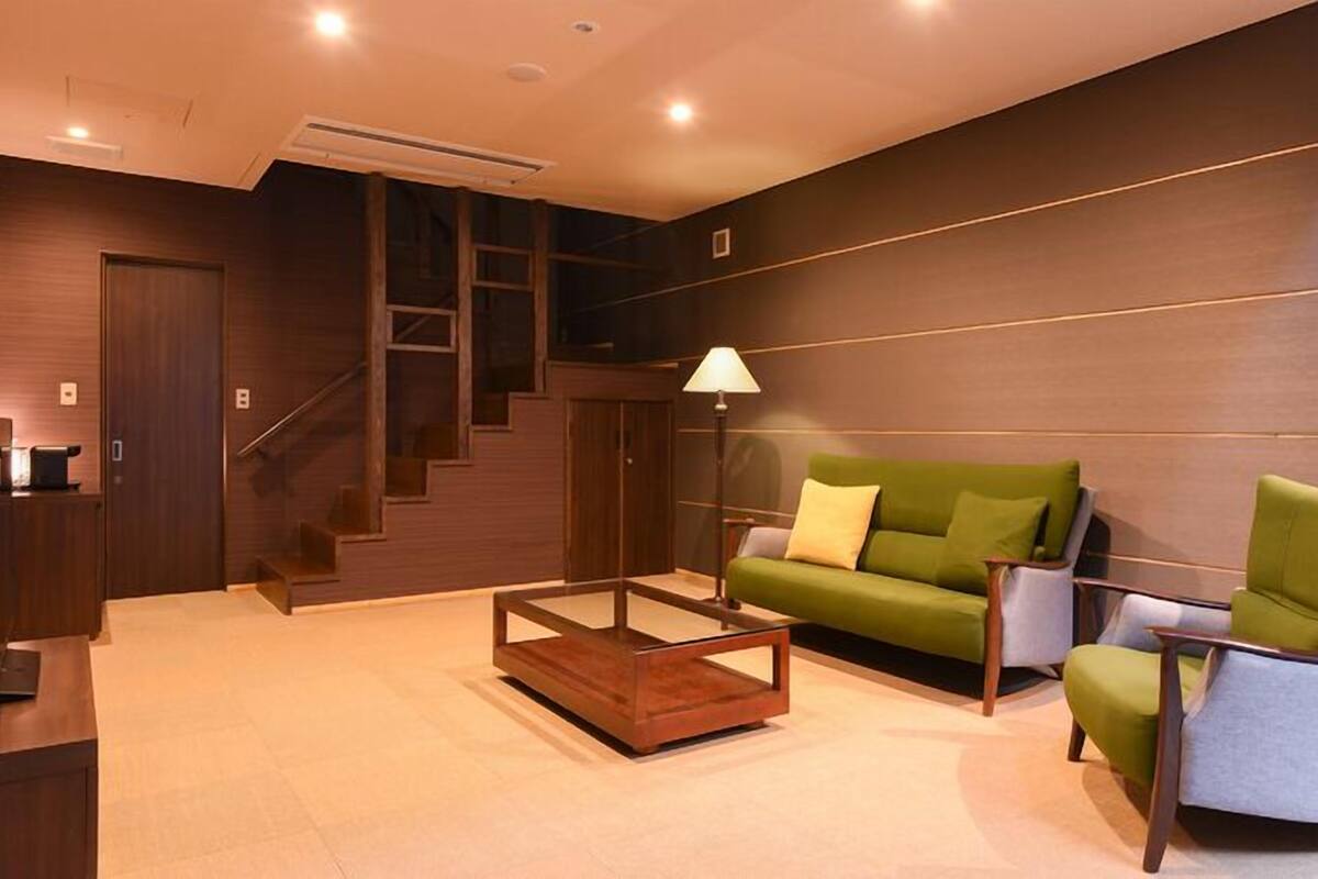 Una sala de estar moderna con una escalera, un sofá verde, una mesita de centro y una lámpara.