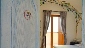 Un dormitorio con una cama, una puerta con un número y vistas al exterior.