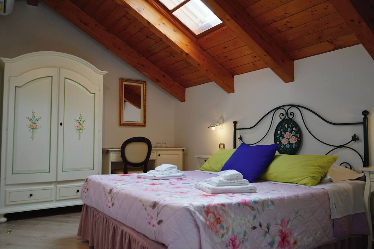 A bedroom with a bed, a wardrobe, a desk, and a mirror.
