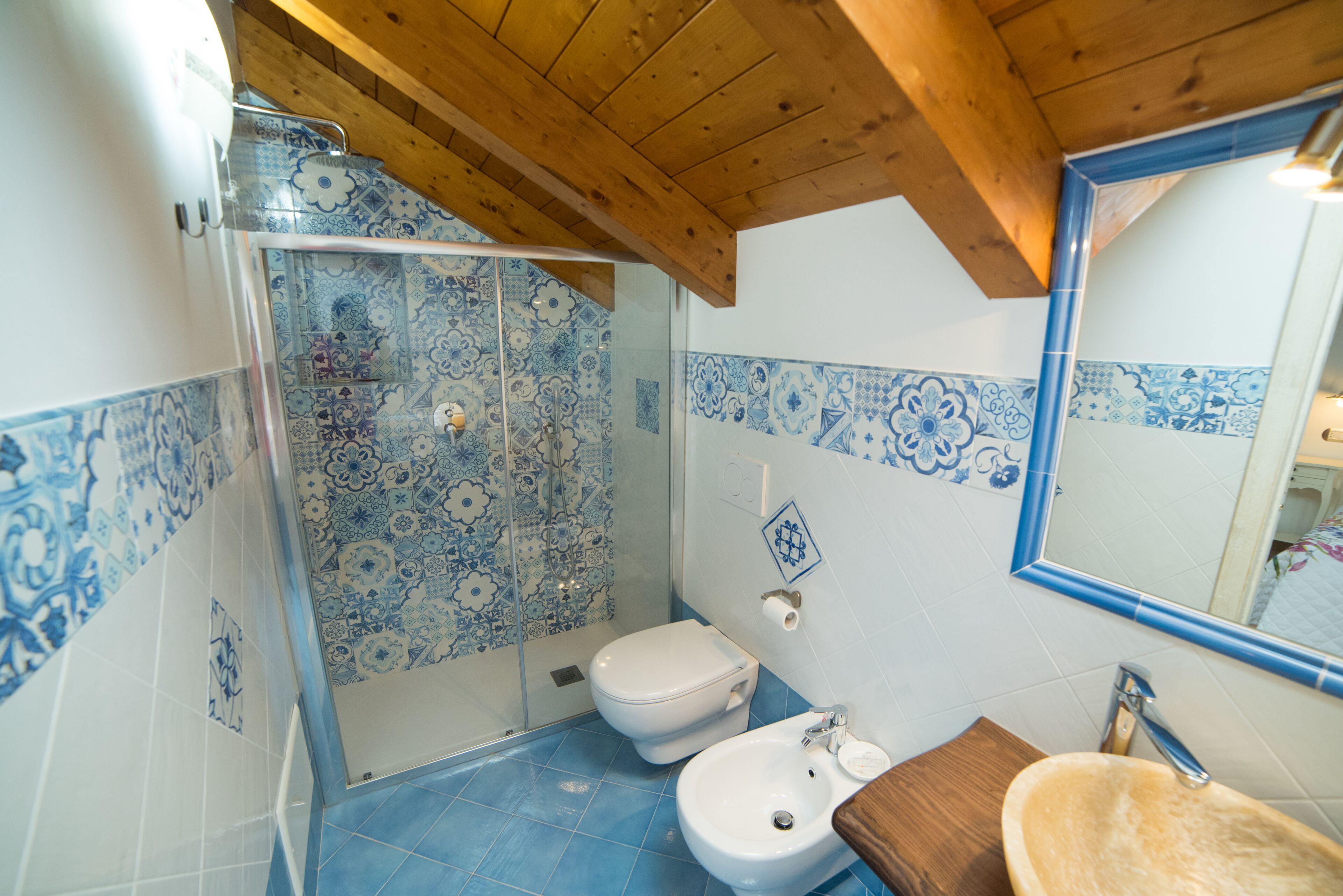 A bathroom with a shower, toilet, sink, and mirror.