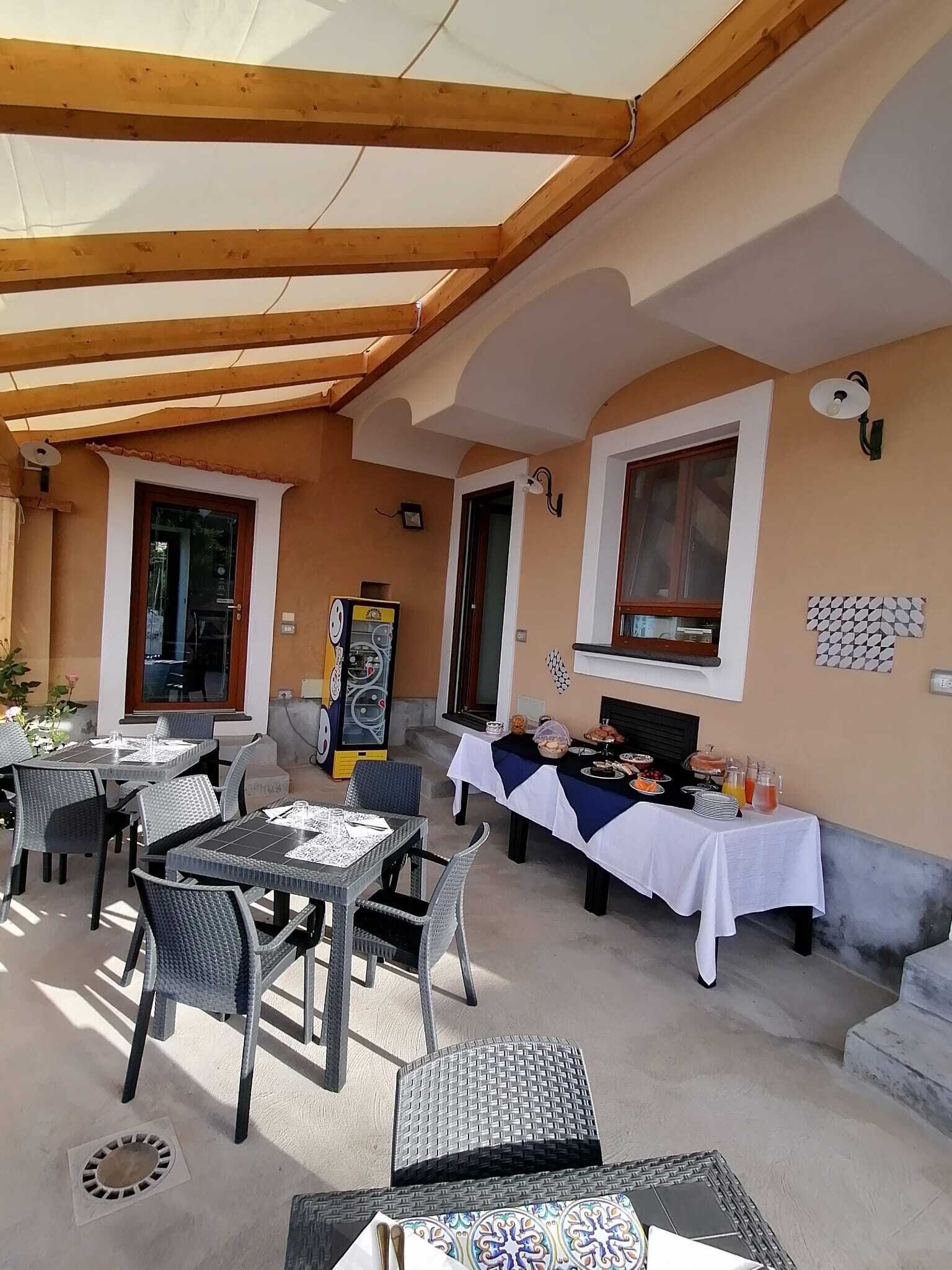 Un espace extérieur aménagé en terrasse, avec des tables et des chaises, un buffet garni de plats et une structure de plafond en bois.