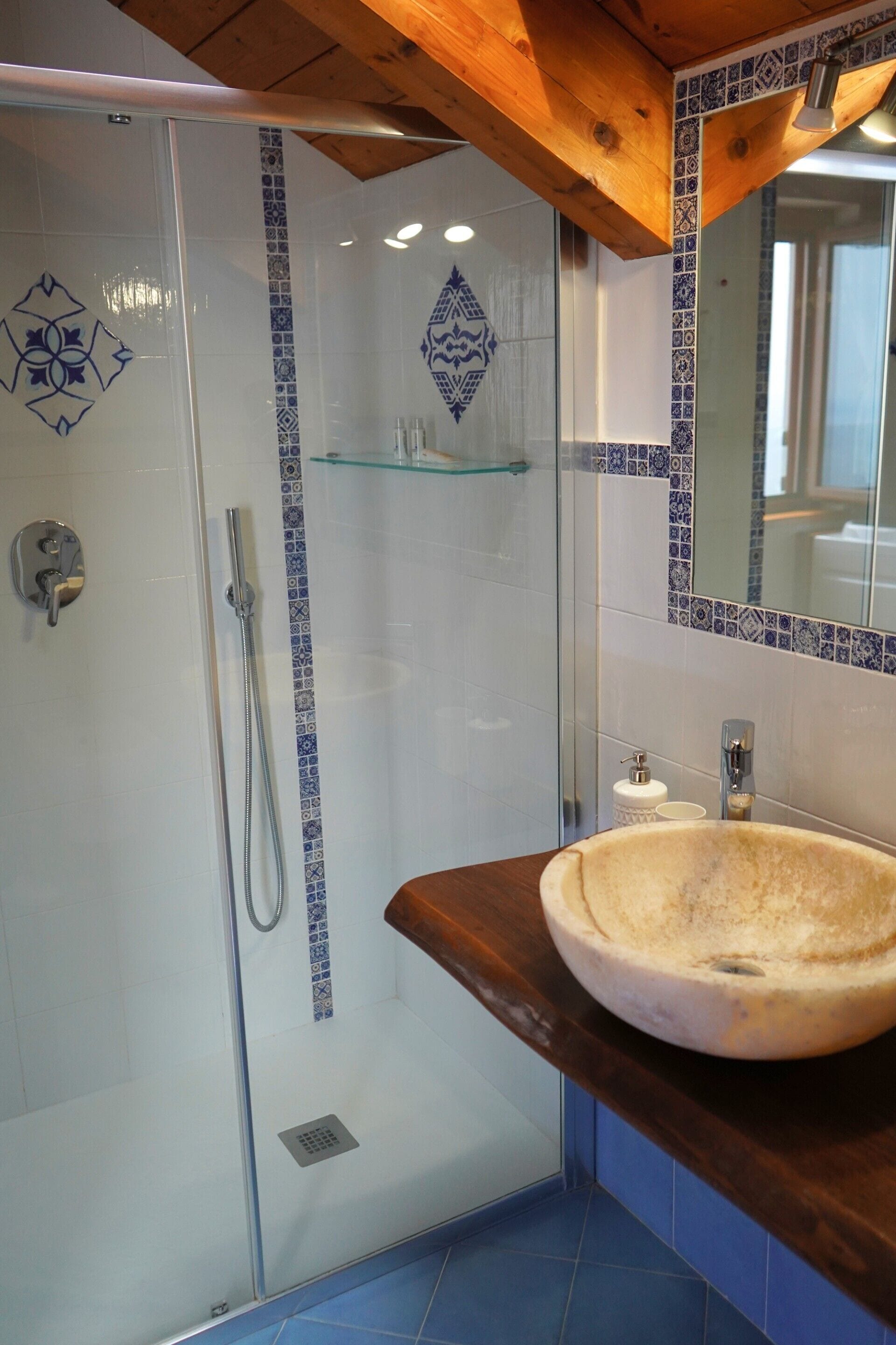 A bathroom with a glass-enclosed shower, a wooden vanity, and a tiled backsplash.