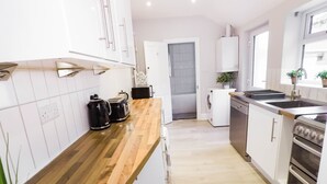 Una cocina moderna con armarios blancos, encimera de madera, horno empotrado y pileta.