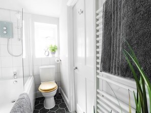 A bathroom with a white toilet, a shower, and a towel rack. - Central Stamford Townhouse (Stamford)