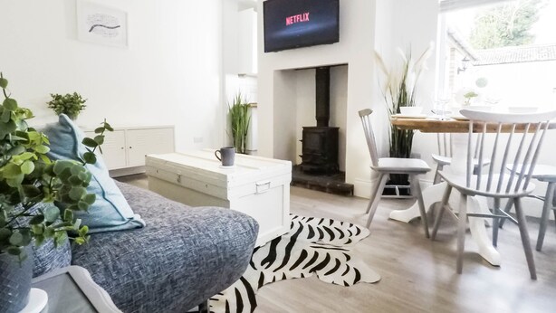 Una sala de estar moderna con sofá, una mesa de centro, chimenea y comedor con sillas.
