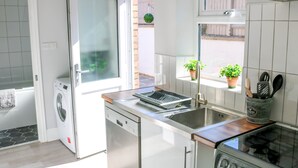 Una cocina compacta con lavadora integrada, un fregadero y una estufa.