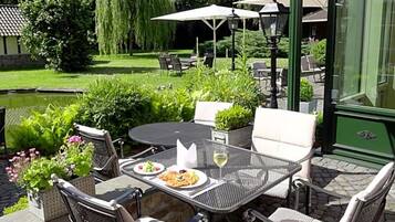 Eine Außenpatio mit einem runden Tisch, Stühlen und Sonnenschirmen.