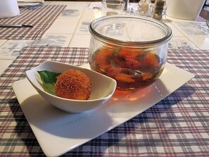 A glass jar with a lid, containing a dark liquid, possibly tea, on a checkered tablecloth.