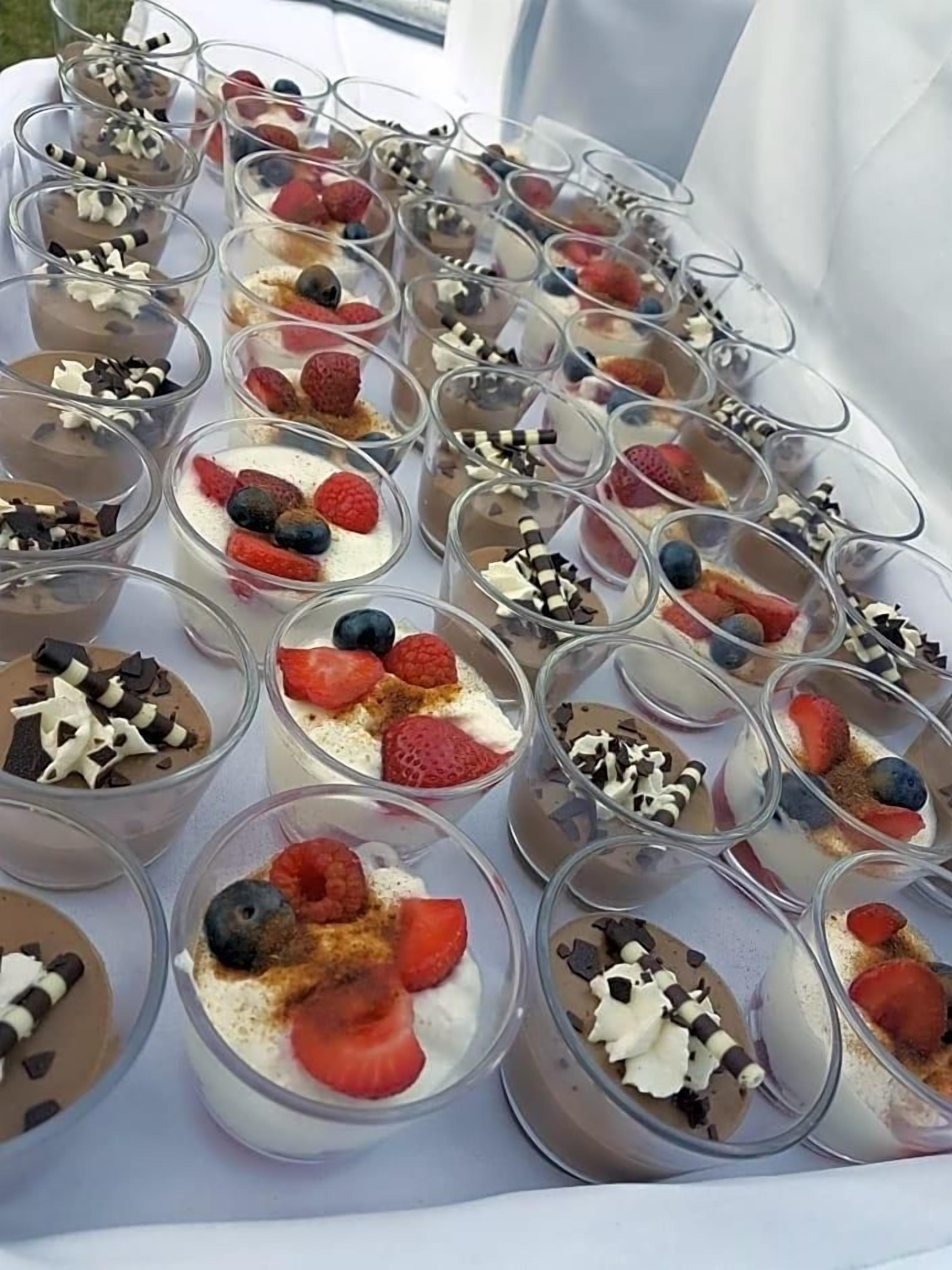 Una mesa con varios vasos de postres dispuestos en filas.