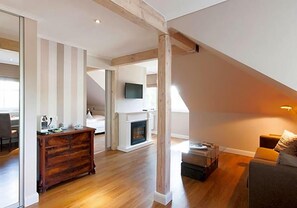 A spacious loft with high ceilings, exposed wooden beams, a fireplace, and a cozy seating area.