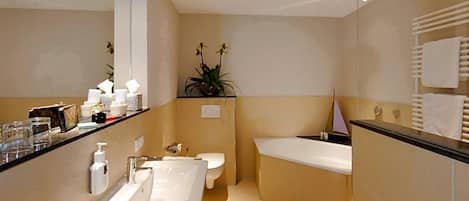 A modern bathroom with a large mirror, a bathtub, a toilet, and a sink.