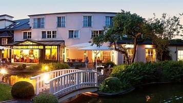 Ein Hotel mit Garten, Teich und Brücke.
