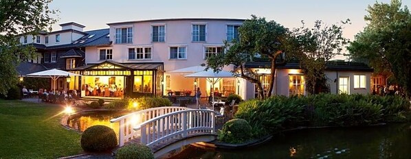 A hotel with a garden, a pond, and a bridge.