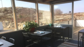 Ein sonnendurchflutetes Zimmer mit einem großen Fenster, einem Blumentopf und einem Tisch mit Stühlen.