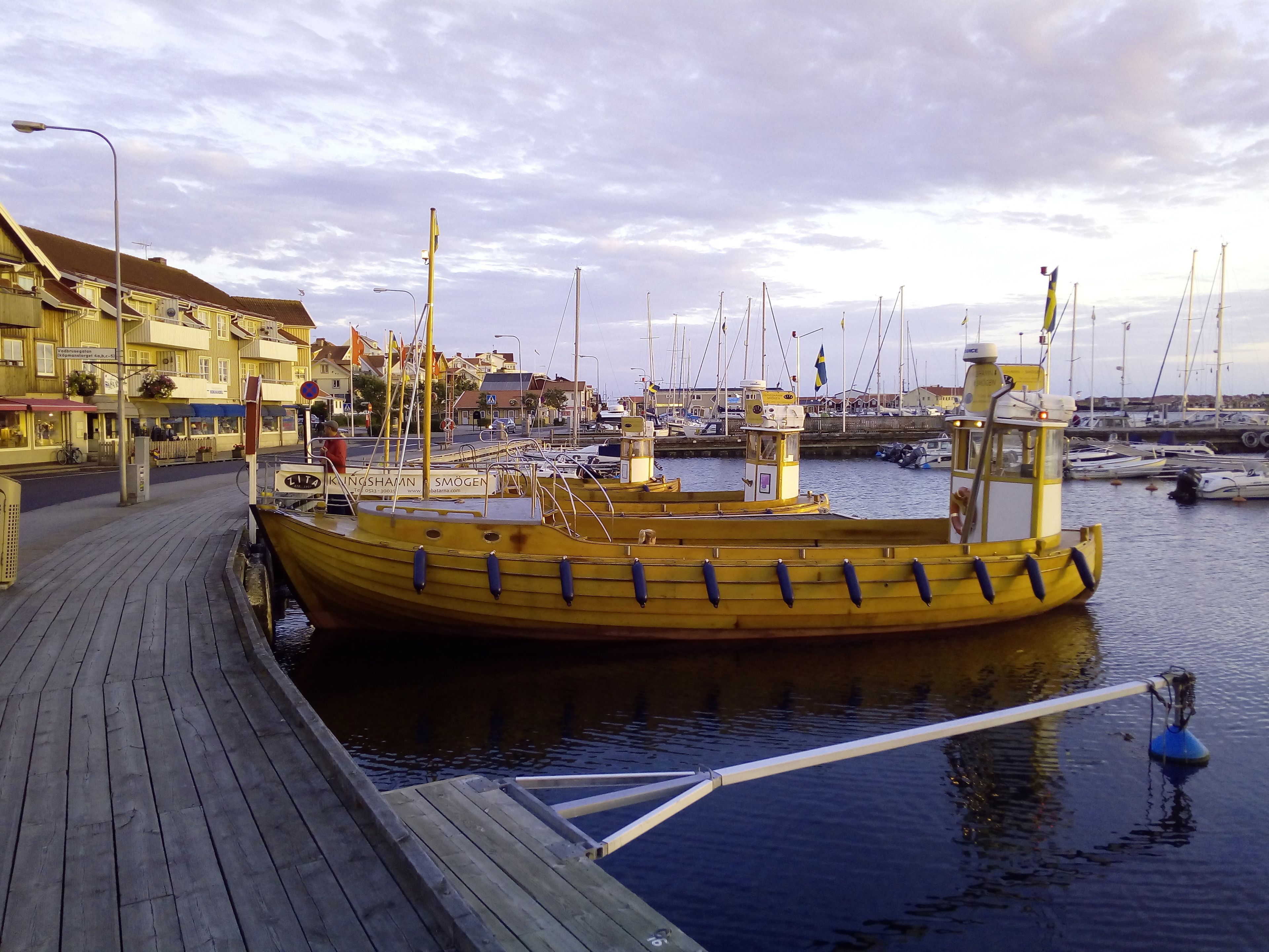 Ein hölzerner Steg mit einem gelben Boot, das in einer Marina liegt.