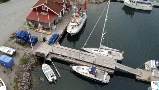 Ein Yachthafen mit vertäuten Booten, ein kleines Gebäude mit rotem Dach und eine Straße, die zum Yachthafen führt.