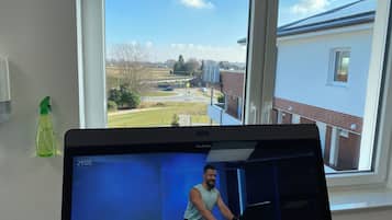 A room with a large window, a Peloton exercise bike, and a green spray bottle on the wall.