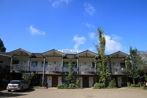 Een hotel met een bord waarop staat 'Waldhotel Zum Bergsee Damme'. Het heeft meerdere balkons met buitenplaatsen en een parkeerplaats ervoor.