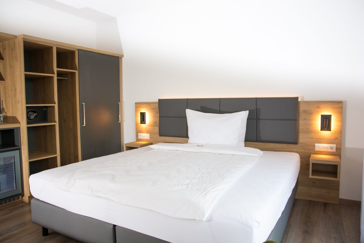 Une chambre d’hôtel moderne avec un grand lit, une armoire en bois et des lampes de chevet.