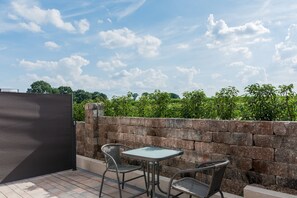 Une terrasse avec une table et deux chaises, un mur en pierre et une vue sur la verdure.