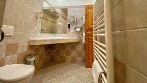 A bathroom with a toilet, sink, mirror, towel rack, and a shower area.