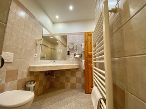 Casa de banho com sanita, lavatório, espelho, porta-toalhas e zona de duche.