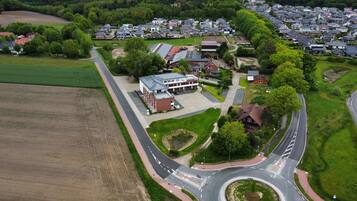 An aerial view of a residential area with a roundabout, houses, and a large building with solar panels.