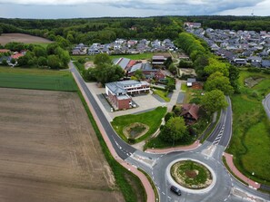 Ein Luftbild eines Wohngebiets mit Kreisverkehr, Häusern und einem großen Gebäude mit Solaranlage.