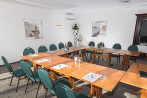 Een vergaderzaal met een lange tafel, meerdere stoelen en een projectiescherm.