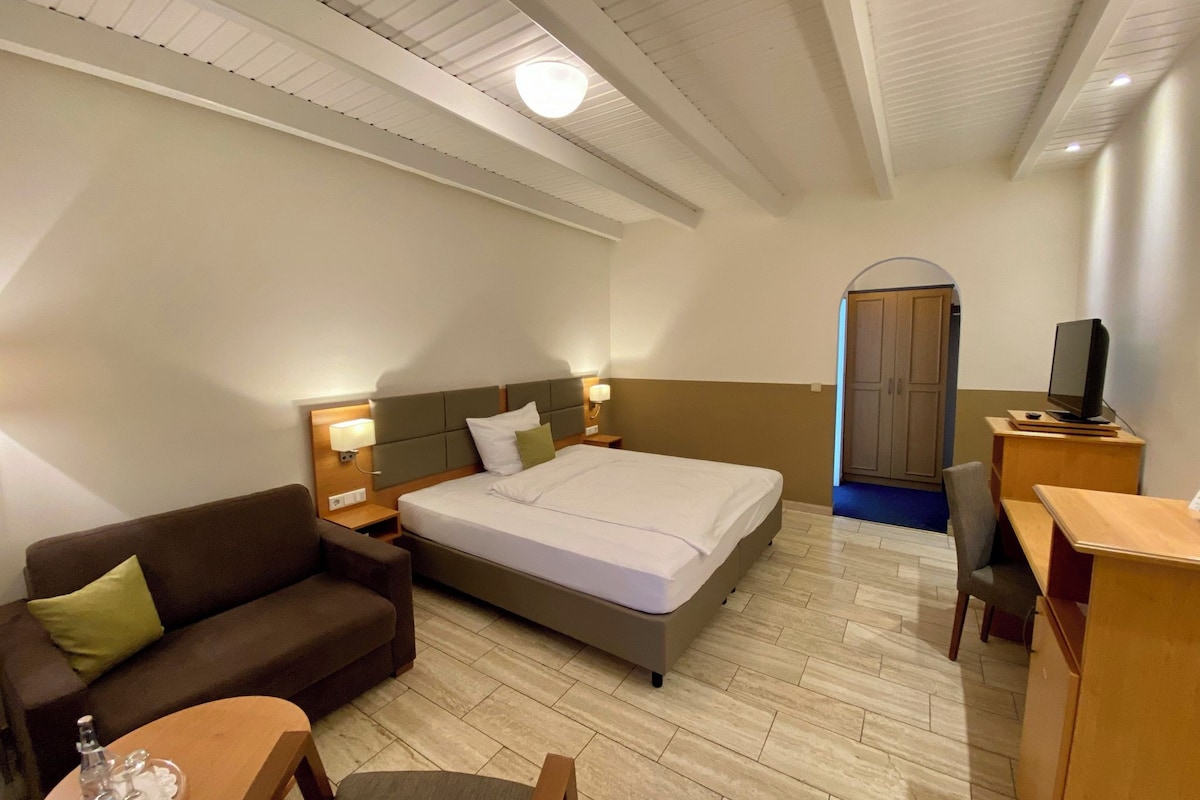 Une chambre d’hôtel équipée d’un lit, d’un canapé, d’un bureau avec un ordinateur et d’une télévision.