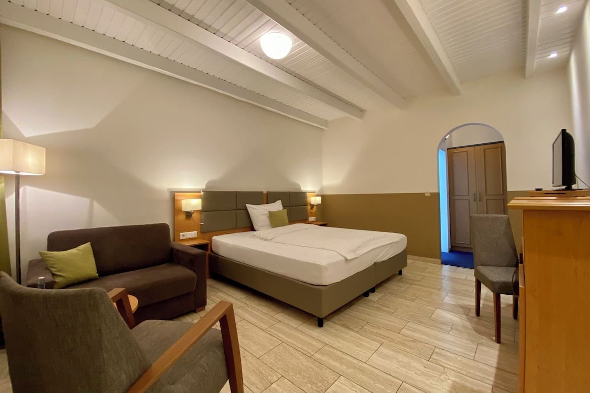 Habitación de hotel con cama, sofá, escritorio y televisión.