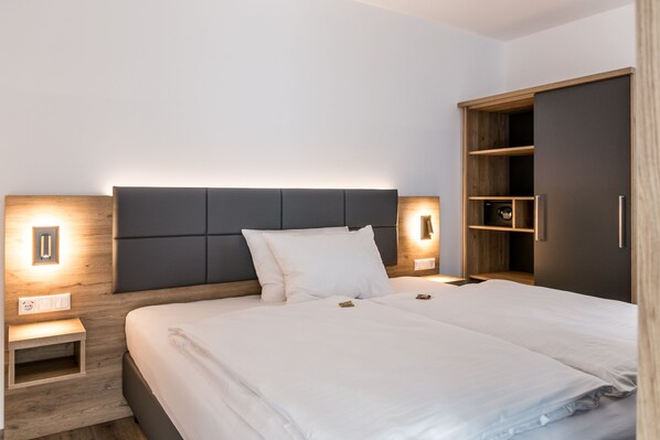Een moderne hotelkamer met een groot bed, een nachtkastje, een garderobe en een wandlamp.