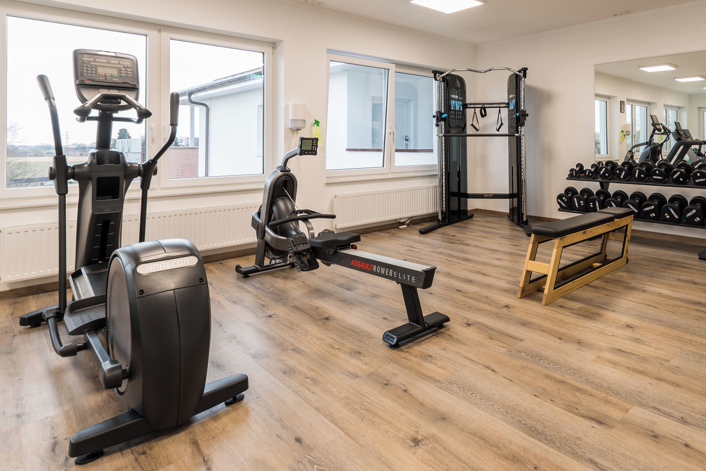 Een sportschool met cardio-apparatuur, krachthonderdelen en gewichten.