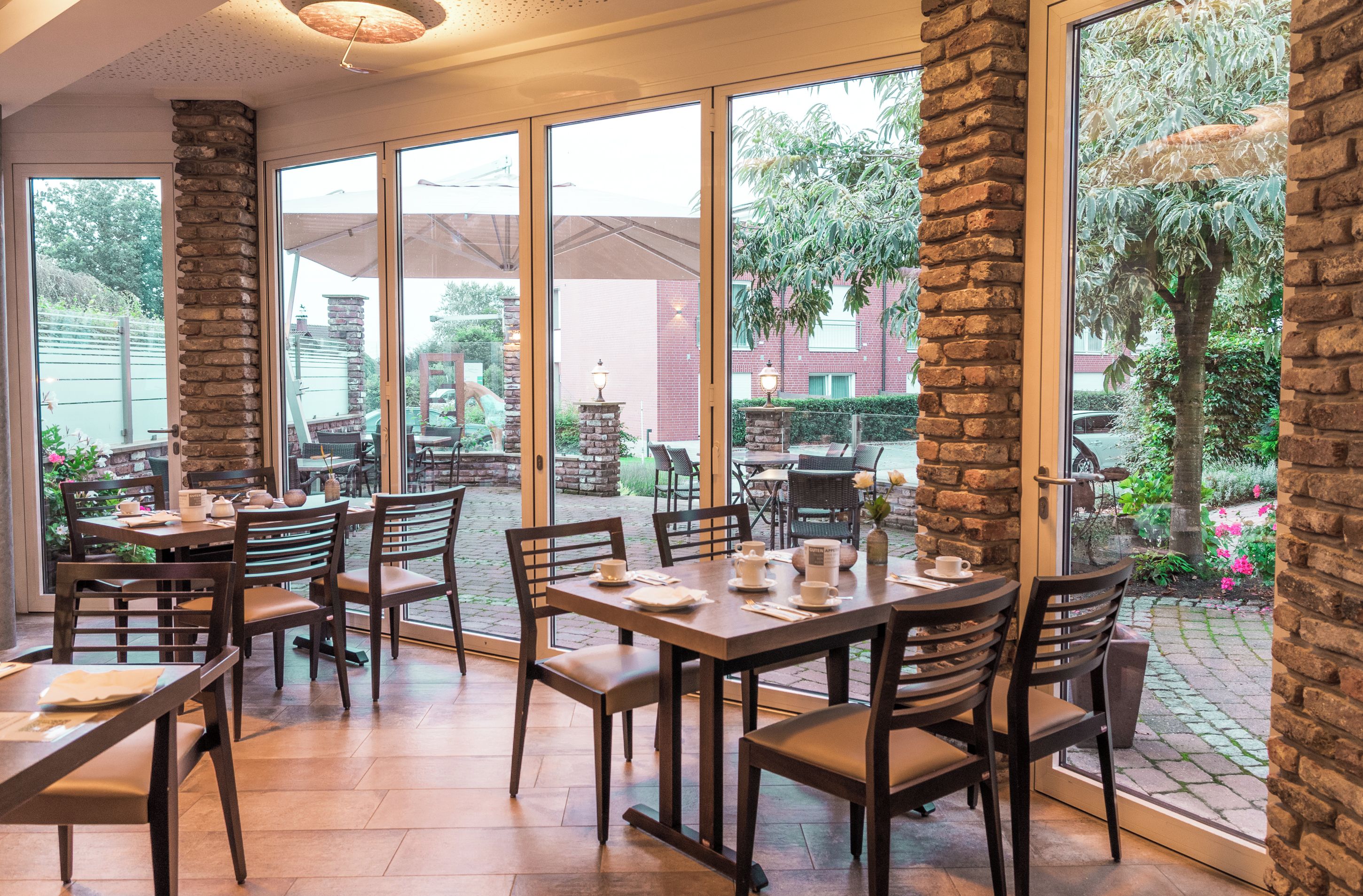 Un restaurant doté de grandes fenêtres, de piliers en pierre et d’une terrasse.