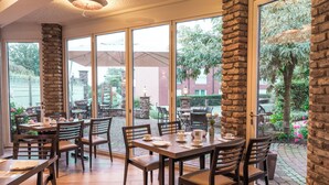 A restaurant with large windows, stone pillars, and outdoor seating.
