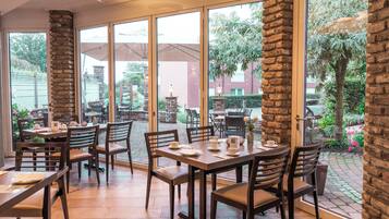 Un restaurant doté de grandes fenêtres, de piliers en pierre et d’une terrasse.