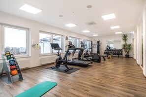 Ein Fitnessraum mit Laufbändern, Ergometer und einem Kettlebell-Ständer.