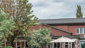 Ein Innenhof mit einem Backsteingebäude, Sitzmöglichkeiten im Freien, einer Pferdestatue und einem Garten.