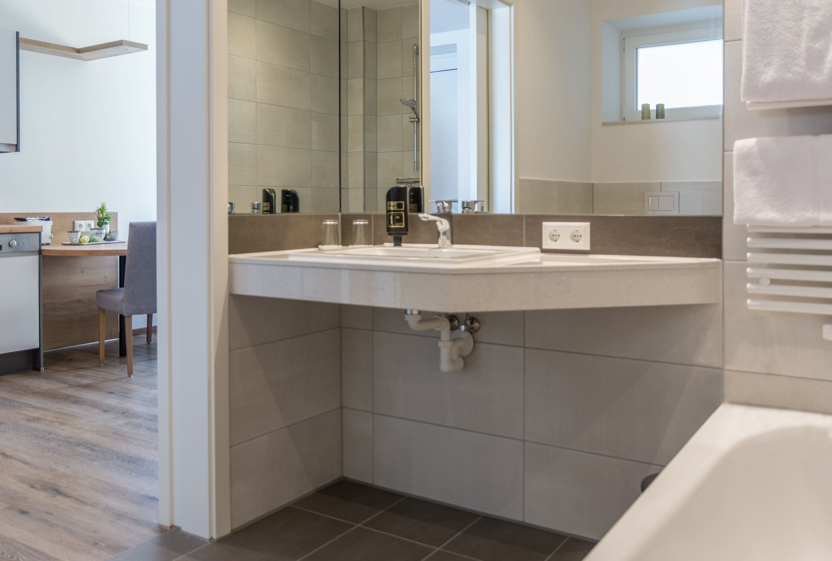 A modern bathroom with a large mirror, a sink, and a shower.