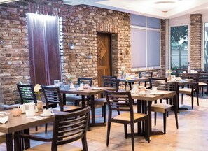 Restaurante com paredes de tijolo, mesas e cadeiras de madeira.