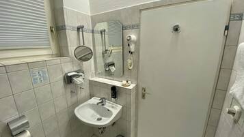 Een badkamer met een wastafel, spiegel, handdoekdispenser en een haardroger.